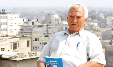 Elderly man sits on rooftop while holding book