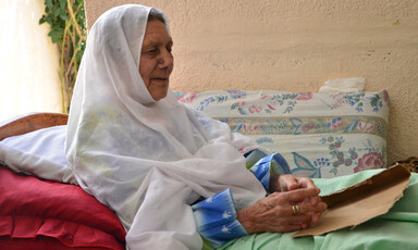 Elderly woman sits in bed