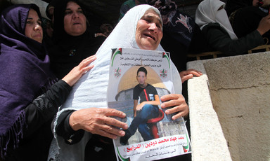 Mourning woman holds poster of slain child