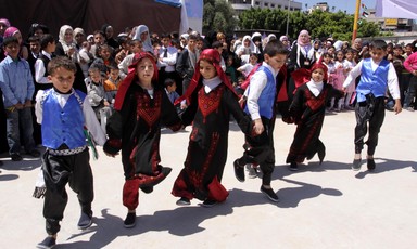 Boys and girls hold hands while performing a line dance