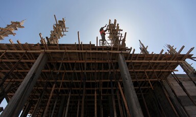 Man hammers on top of partially-constructed building