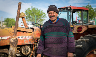 Smiling middle-aged man stands in front of farming equipment