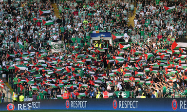 Dozens of football spectators hold up Palestinian flags in full stadium