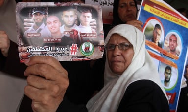 Woman in headscarf holds photo showing four men abducted in Egypt