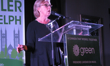 Green Party leader Elizabeth May speaks into microphone at podium