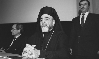 Black and white photo of Hilarion Capucci in archbishop's robes sitting at table