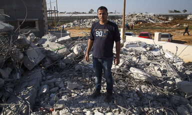 Young man stands on rubble of demolished home