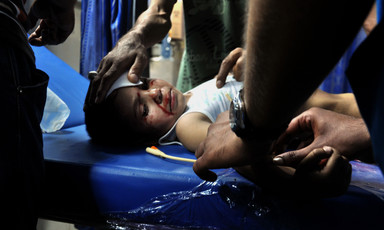 A wounded boy lying on a stretcher receives treatment at hospital