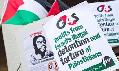 Protest signs read: G4S profits from Israel's illegal detention and torture of Palestinians