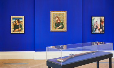 Installation view of three works on canvas on wall with vitrine containing rifle in foreground