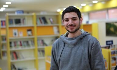 Smiling young man stands in library