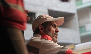 Profile of bearded man wearing paramedic's uniform and cap sitting in front of building