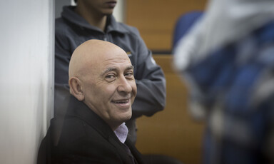 Basel Ghattas smiles at camera while sitting down in courtroom