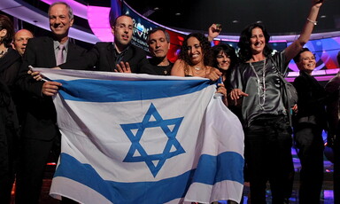 Group of people on Eurovision stage hold Israeli flag