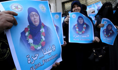 Close-up of poster being held by women showing Lina al-Jarbouni wearing a garland of flowers around her neck 