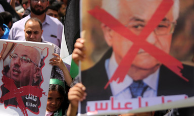 Protesters carry a large photo of Mahmoud Abbas with a red X across his face