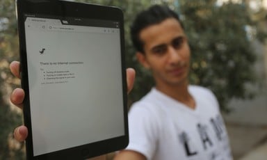 Young man holds up electronic tablet showing an Internet browser error stating, There is no Internet connection