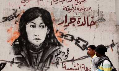Two Palestinian children walk past a mural of Khalida Jarrar, a member of the Popular Front for the Liberation of Palestine, who remains jailed in Israeli prisons.