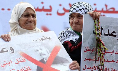 Elderly women hold up posters protesting the Balfour declaration
