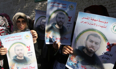 Three Palestinian women hold up posters of Bilal Diab at a protest to show solidarity with Palestinian prisoners held in Israeli jails in Gaza City.