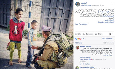 Screenshot of COGAT Facebook post of photograph of kneeling Israeli soldier carrying rifle shaking the hand of a young Palestinian boy as a girl stands nearby