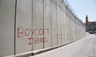 Red graffiti on the Israeli apartheid wall dividing the East Jerusalem neighborhood Ras al-Amud from the West Bank town of Abu Dis reads, "Boycott Israel", on 26 March 2012.