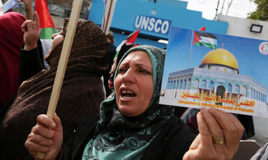 Woman holds photo of Dome of the Rock with the message Jerusalem is the eternal capital of Palestine