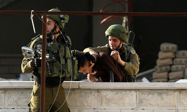 Two Israeli soldiers violently arresting a Palestinian boy. 