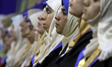 Photo shows row of young women wearing headscarves and graduation robes