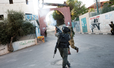 Photo shows soldiers firing tear gas in front of gate to Aida camp that has a giant key on top of it