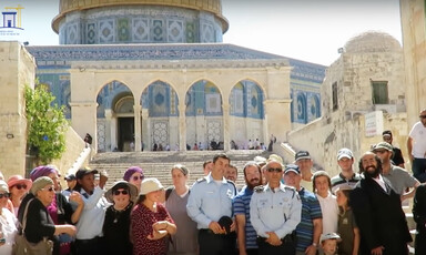 Three Israeli police are seen standing with group of civilians in front of stairs leading up to the Dome of the Rock