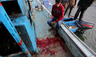 Man sits on edge of ship near pool of blood