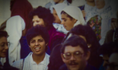 Smiling young woman stands among crowd of men and women