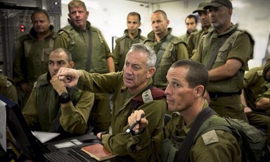 Ben Gantz dressed in military uniform points as other military people watch him