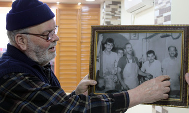 Man in wool hat looks at framed photo he is holding up