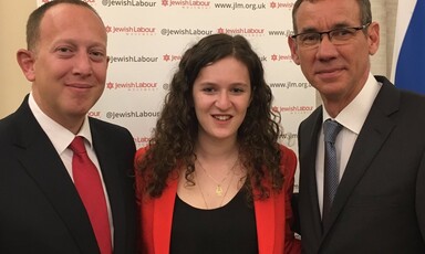 A woman flanked by two men in suits