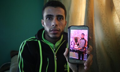 Young man in athletic wear holds up phone showing him receiving a trophy