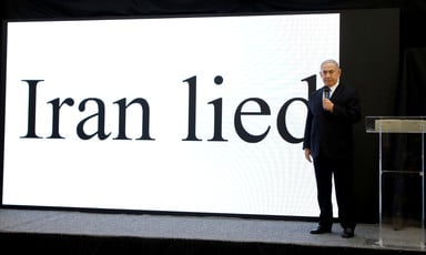 Netanyahu stands on stage with Iran lied in giant letters projected on a screen behind him