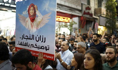Protesters with a banner that reads "Razan al-Najjar is trusting you with her family. Lift the sanctions on Gaza."