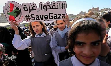 Girls in school uniform hold sign reading #SaveGaza in English and Arabic