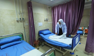A woman nurse folds a sheet on a bed in an empty hospital room