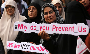 Women hold signs saying Why do you Prevent Us and We are NOT Numbers