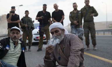Palestinians sit near Israeli police during an early morning raid. 