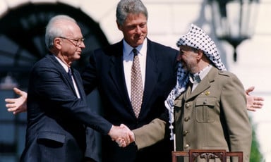 Photo shows Yitzhak Rabin and Yasser Arafat shaking hands while Bill Clinton extends his arms behind them