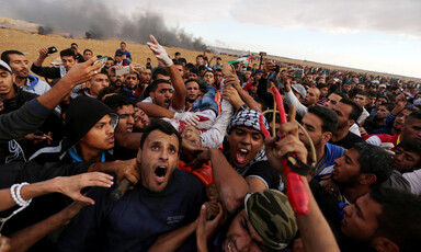 Crowd carries young man wearing white T-shirt covered in blood on stretcher