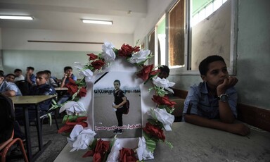 Wreathed photo of boy standing at protest sits on desk in a schoolroom with boys sitting at the desks