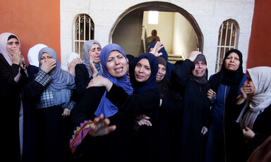A group of mourning women stand in front of arched doorway