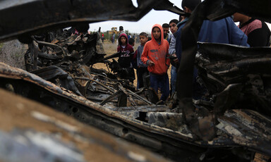Boys look at wreckage of burned-out vehicle
