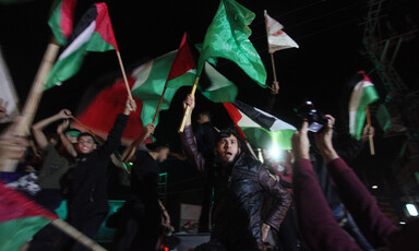 Young men wave the national flag and the Hamas flag at night