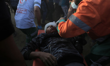 An emergency medic leans over a youth laying on a stretcher with his head wrapped in gauze
